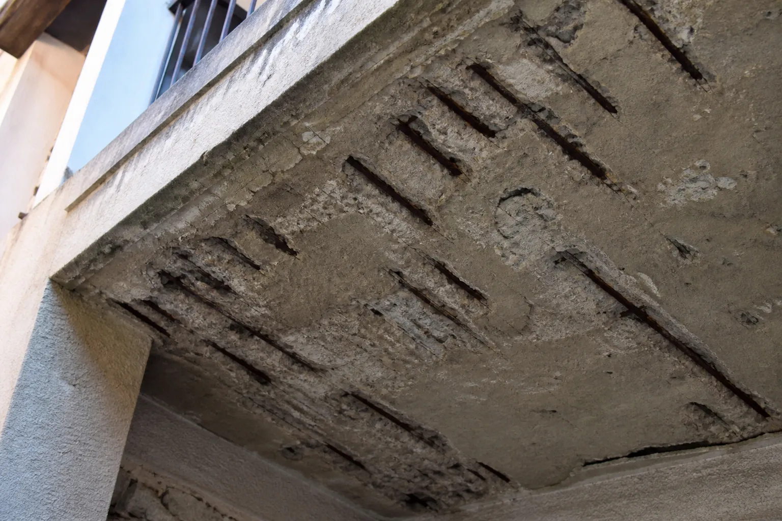 Sous-face de balcon en béton avec éclat et armature apparente