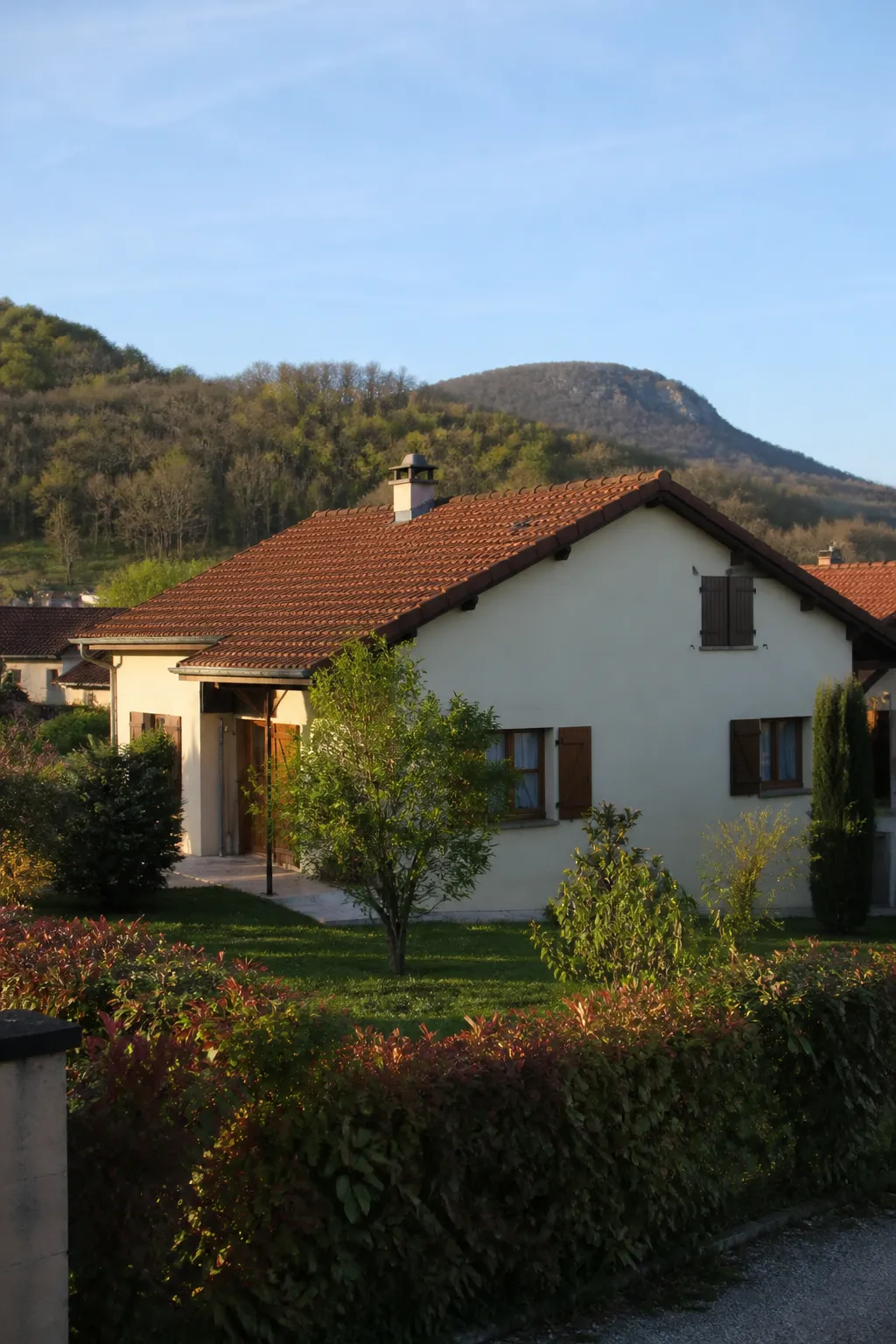 Maison individuelle en crépi clair dans une commune de l’Ain, vue depuis la rue