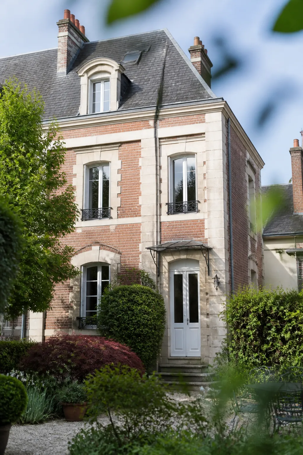 Maison bourgeoise en brique et pierre avec jardin dans une ville du centre de la France