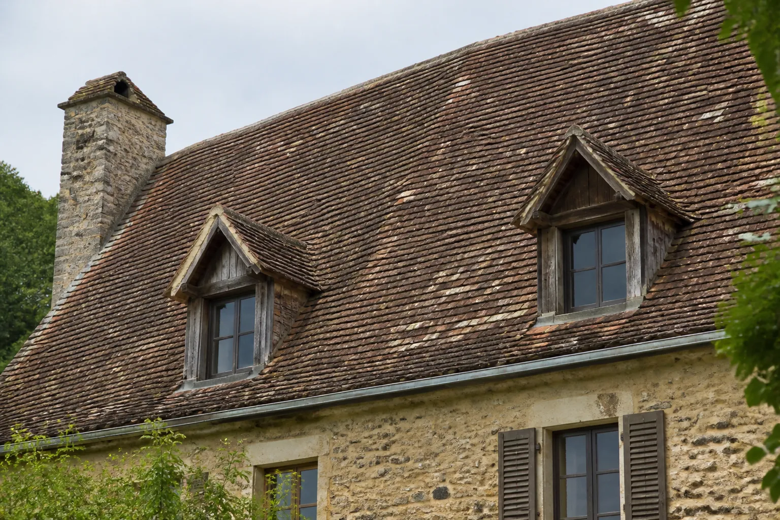 Toiture en tuiles plates et lucarnes sur une maison ancienne