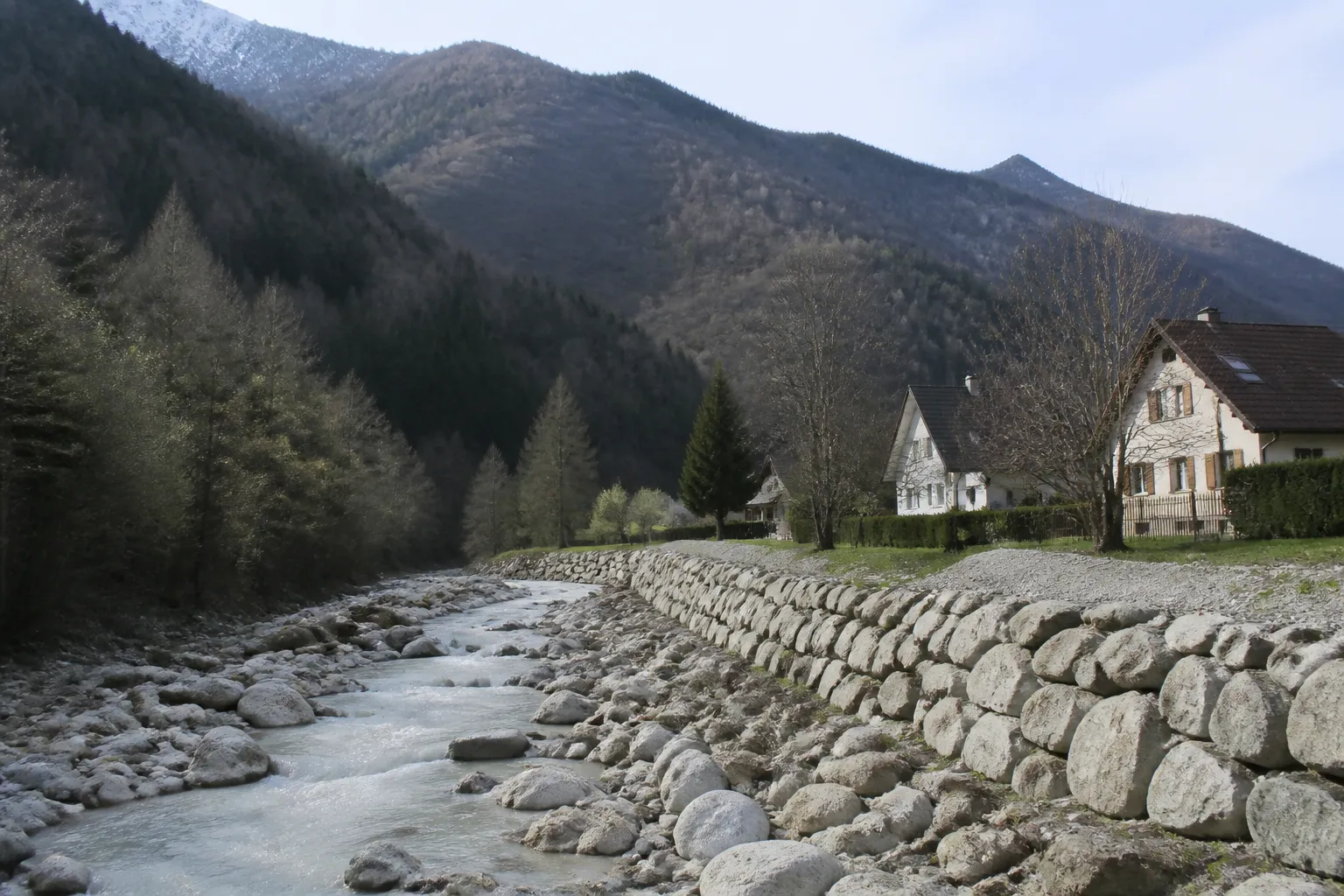 Torrent de montagne à lit de pierres longé par une digue en enrochement