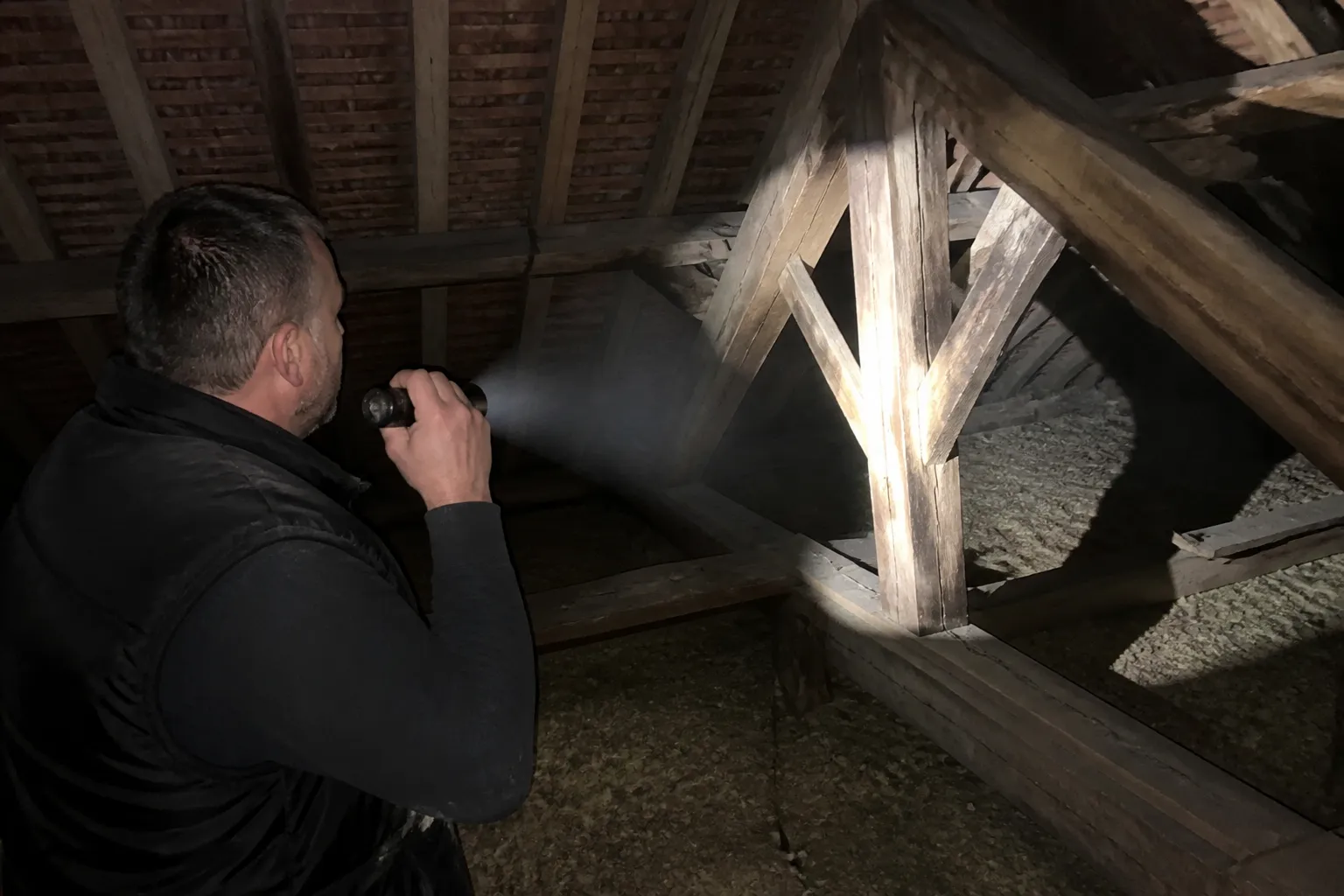 Charpente en bois inspectée à la lampe dans des combles accessibles