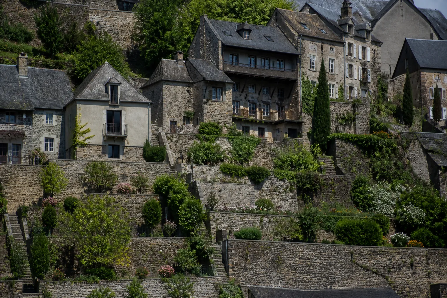 Maisons étagées sur une pente avec murs de soutènement et jardins