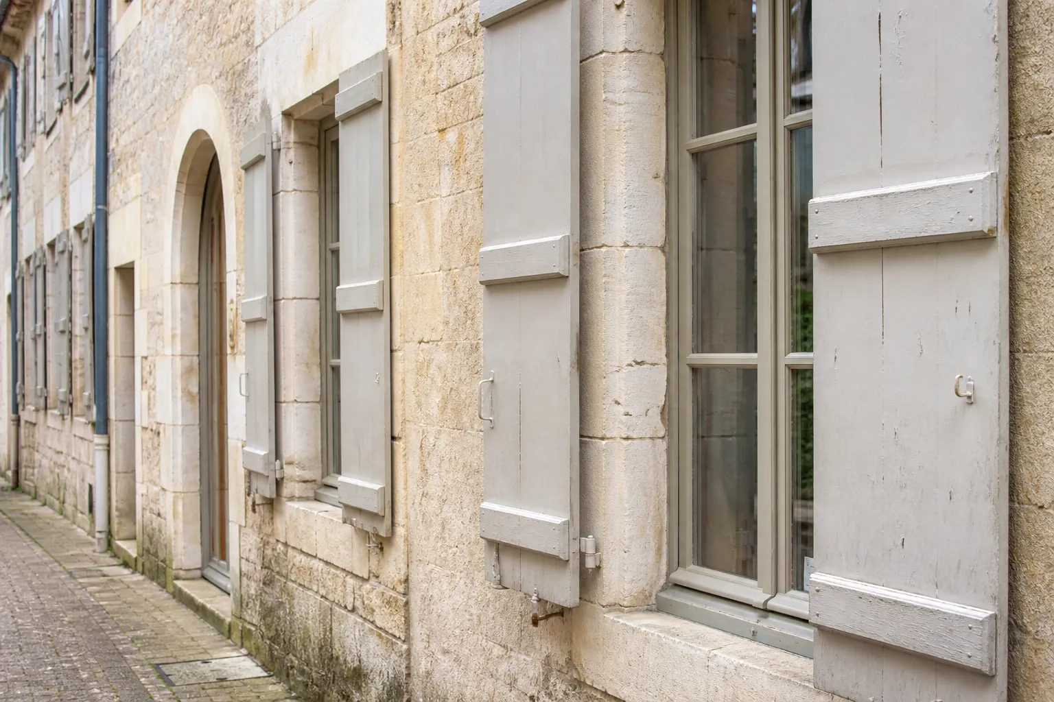 Fenêtres en bois peint et volets battants sur une façade ancienne en pierre