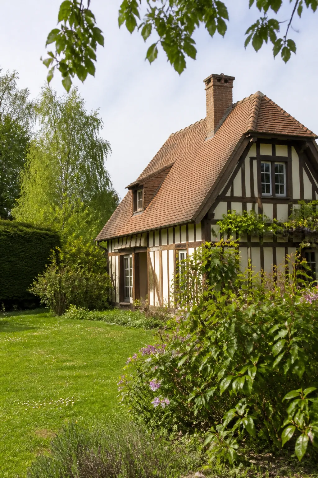 Maison normande à colombages dans un jardin verdoyant
