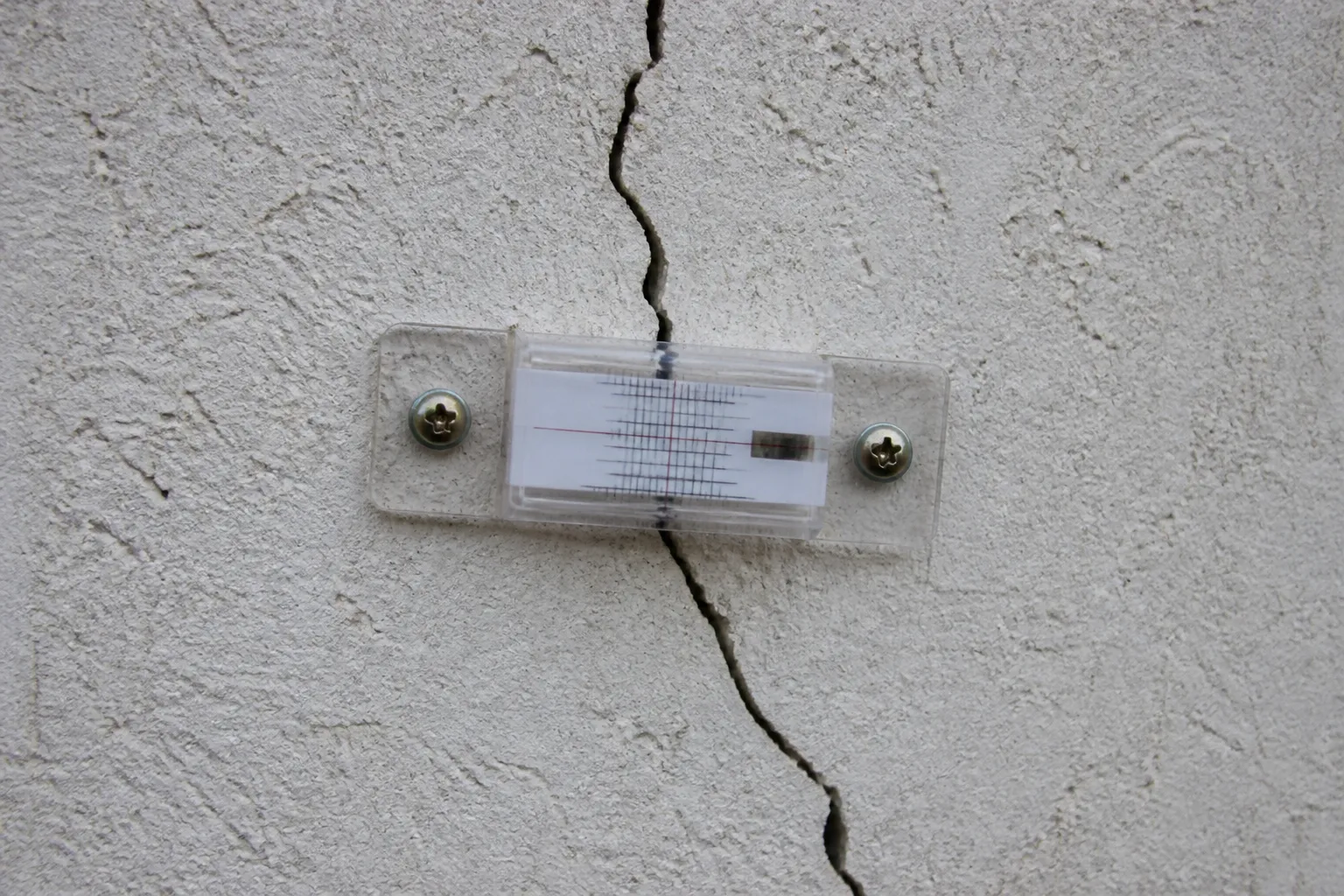 Fissure sur une façade de maison relevée avec un fissuromètre