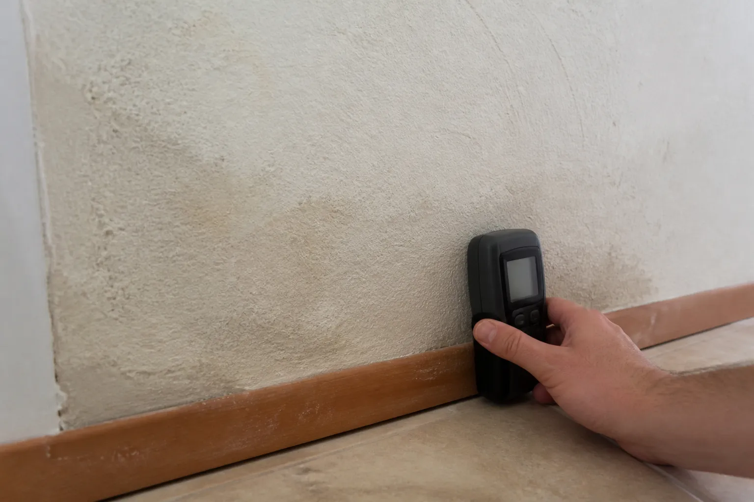Mesure de l’humidité au pied d’un mur intérieur avec un humidimètre
