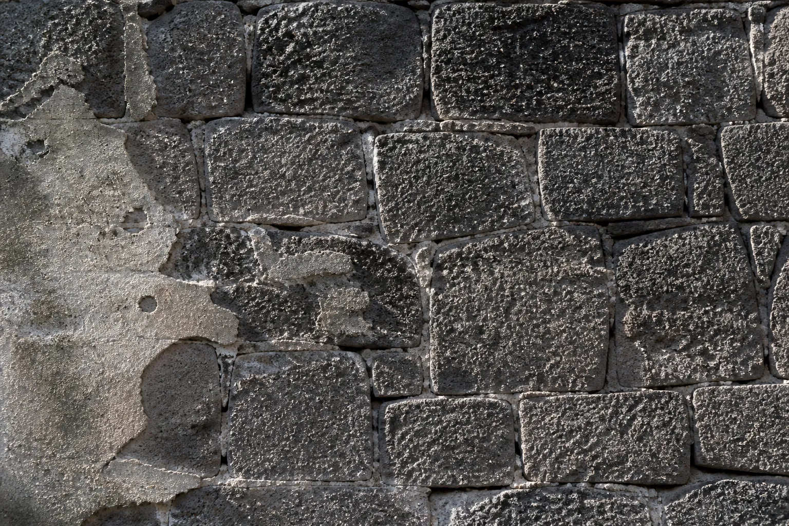 Mur ancien en pierre sombre avec joints à reprendre, observé lors d’une expertise