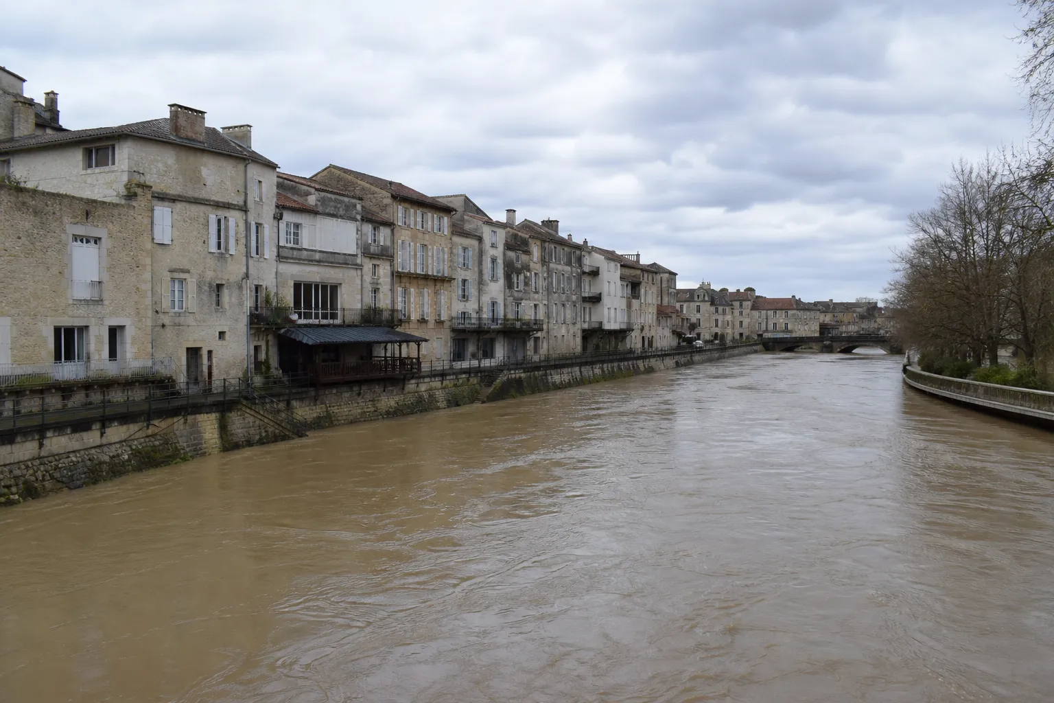Large rivière en crue bordée de maisons dans une ville du sud-ouest