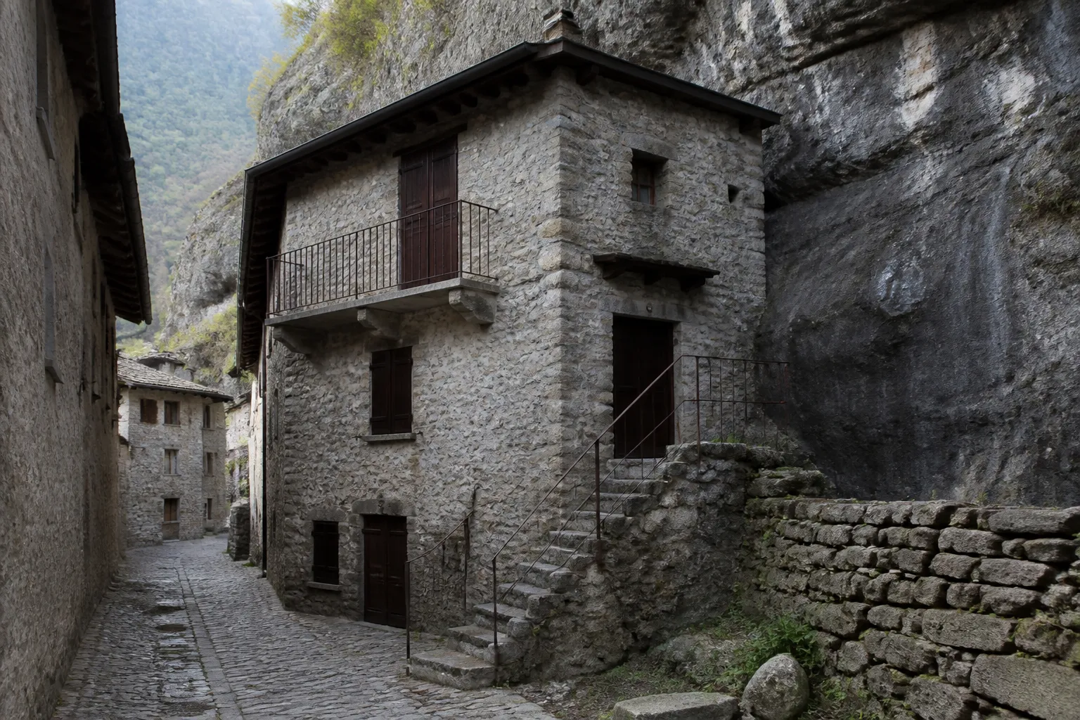 Maison ancienne adossée à une paroi rocheuse dans une ville de Haute-Loire