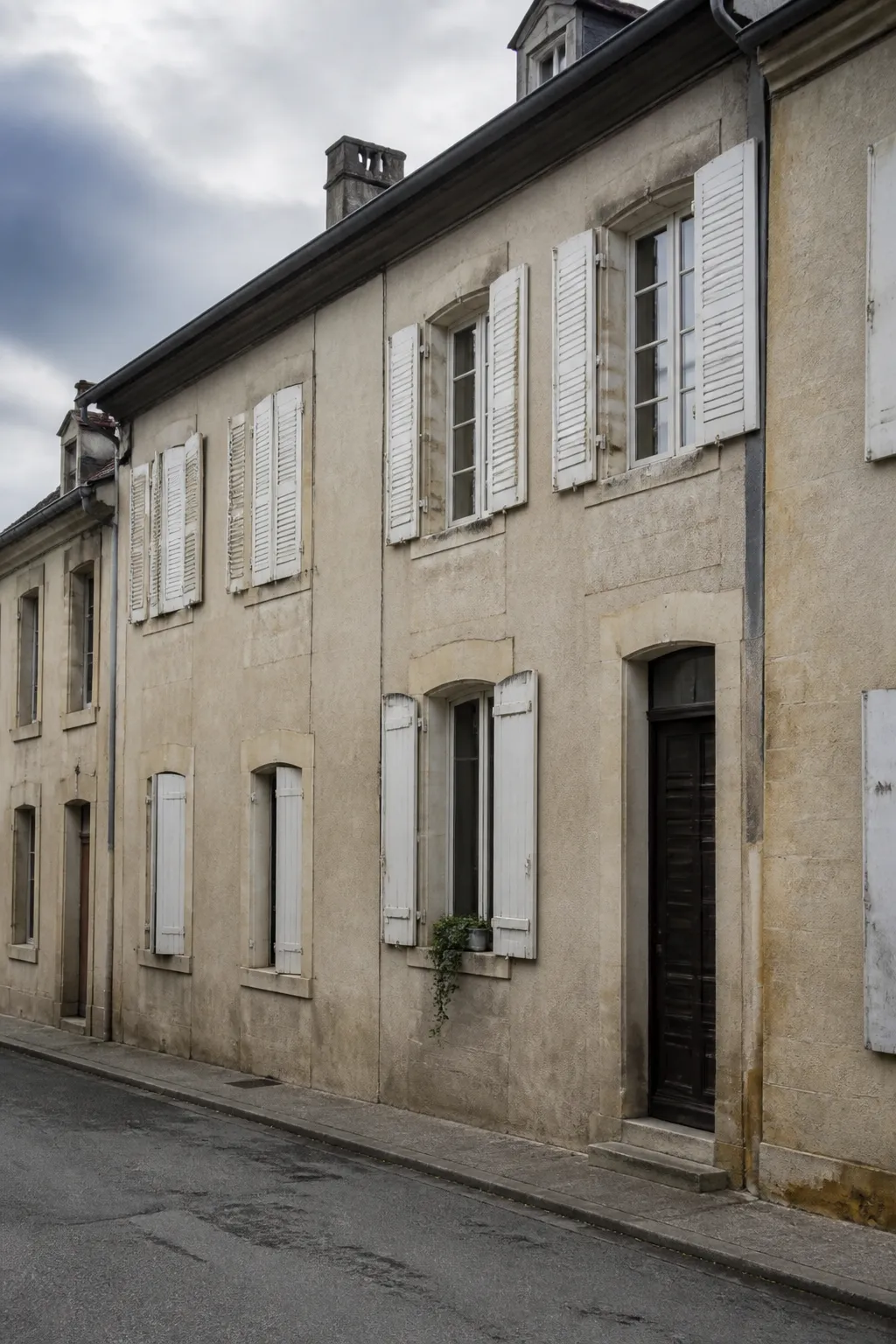 Façade de maison de ville en pierre calcaire avec volets dans une rue de Meuse