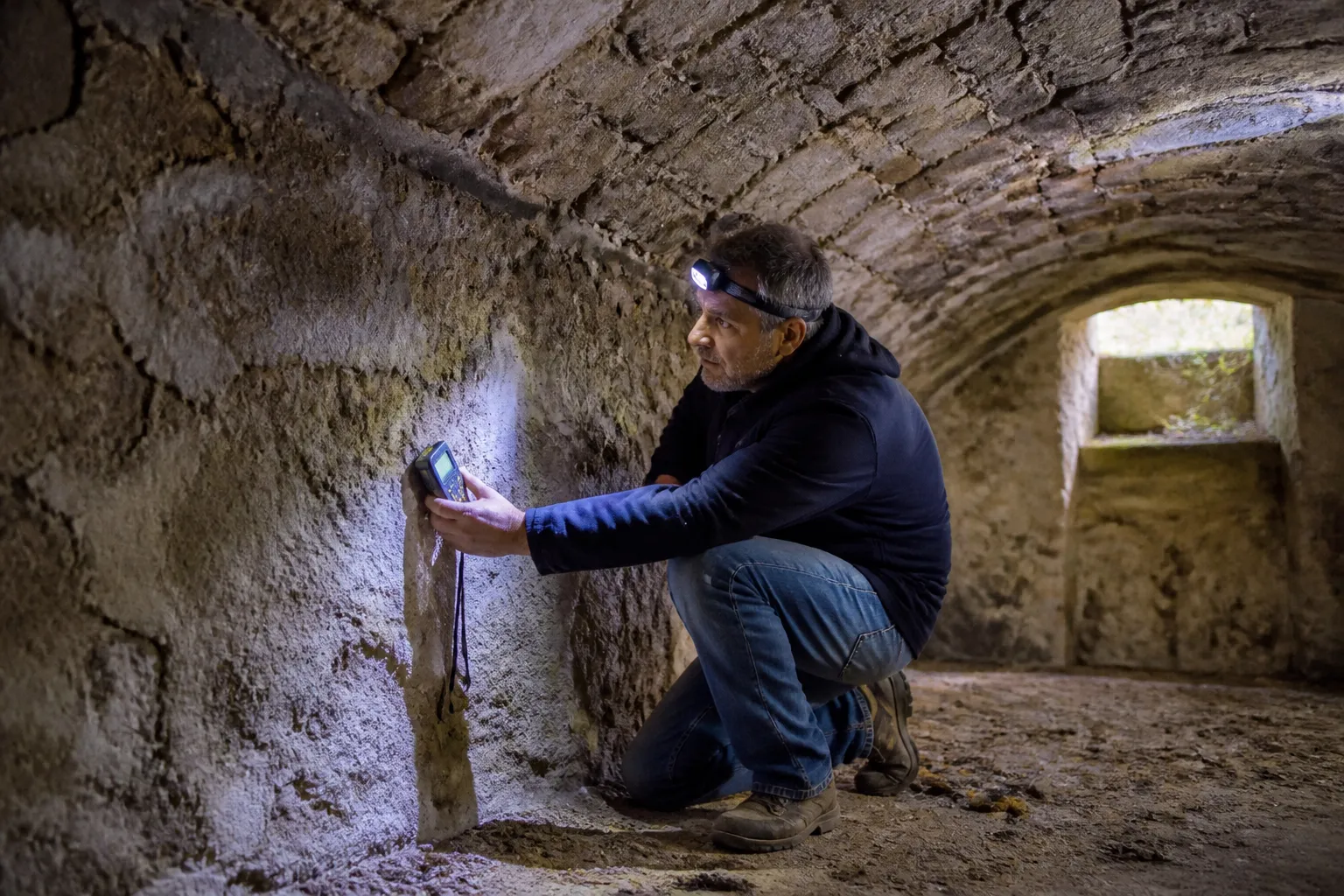 Expert mesurant l’humidité d’un mur de cave voûtée