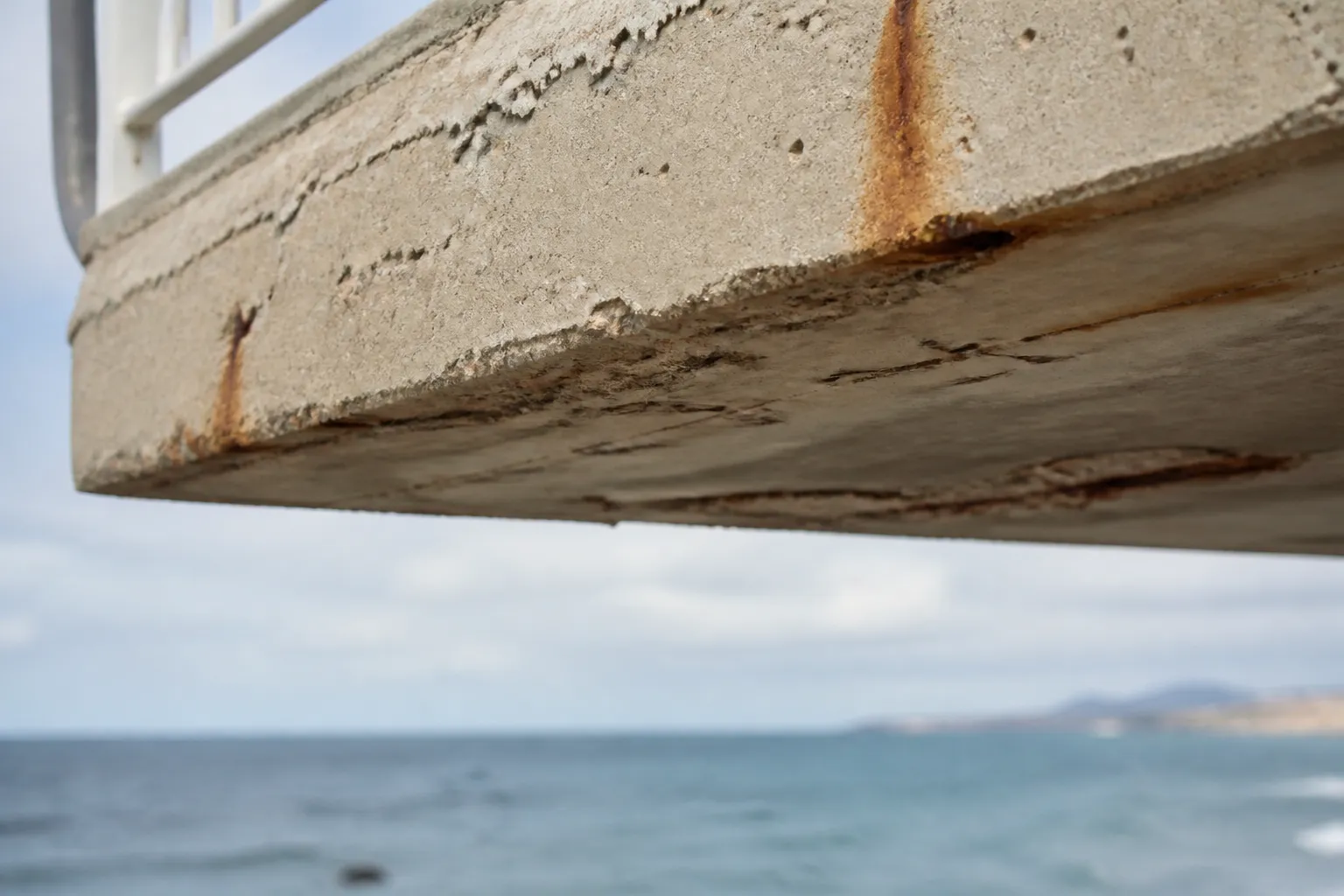 Sous-face de balcon en béton observée par un expert près de la mer