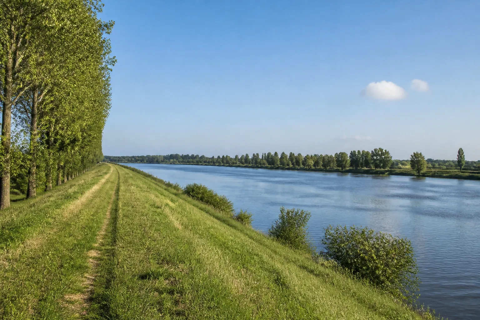 Digue enherbée longeant une large rivière en plaine