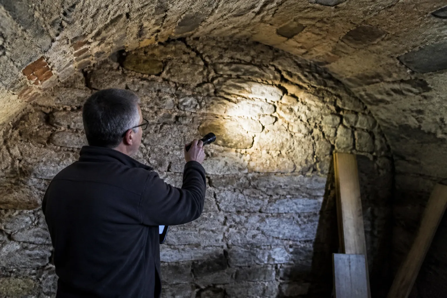 Expert en bâtiment examinant le mur d’une cave voûtée