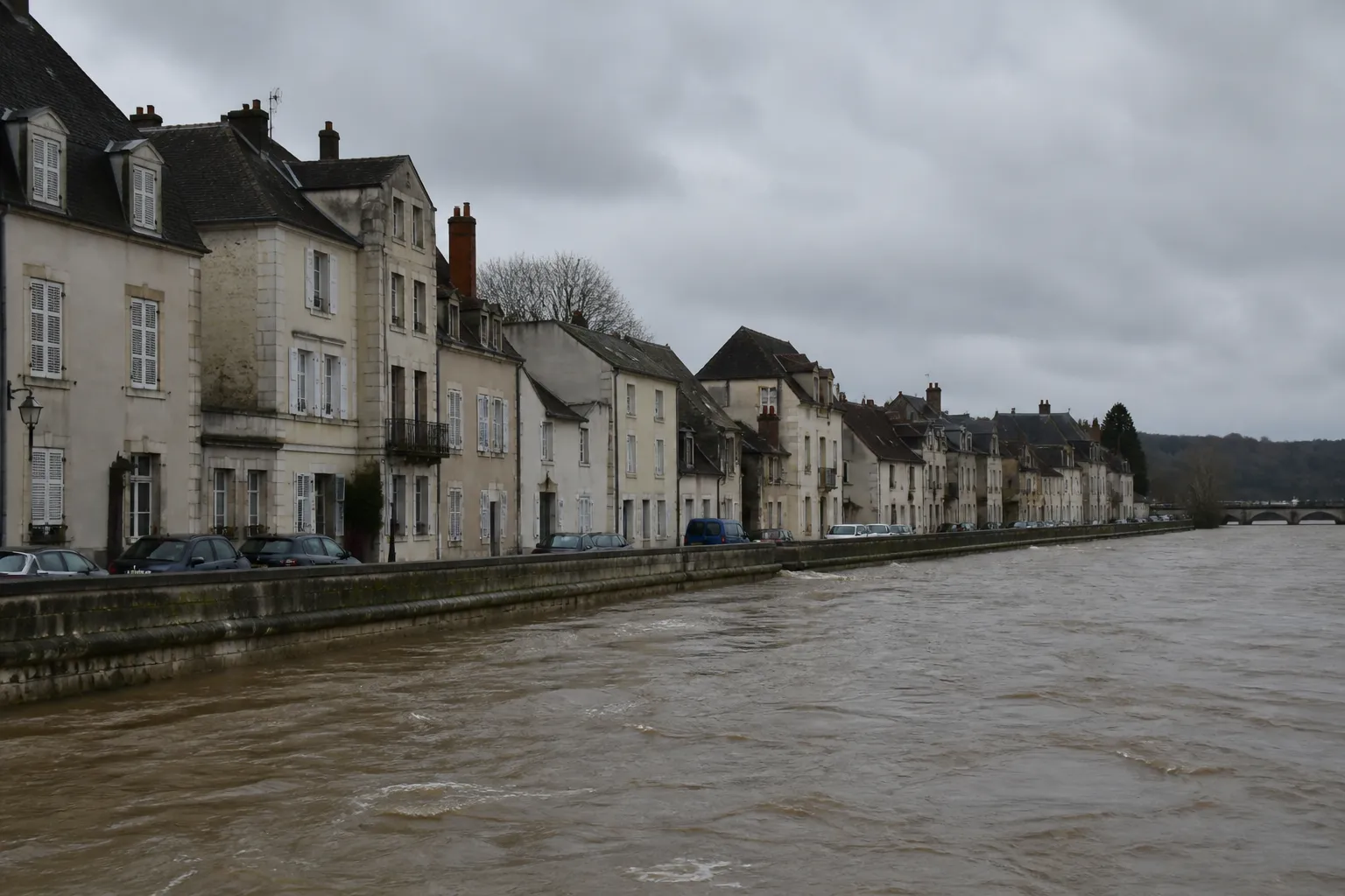 Rivière large en crue bordée de quais et de maisons