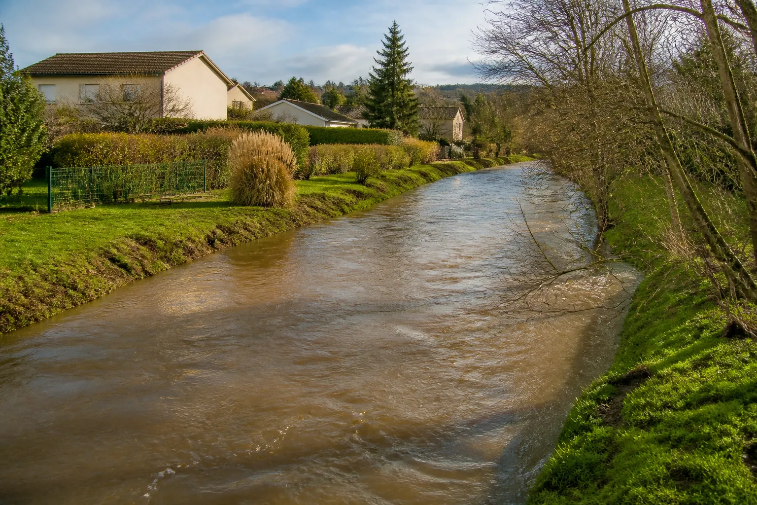 Rivière en crue lente longeant des maisons, illustration du risque inondation par débordement