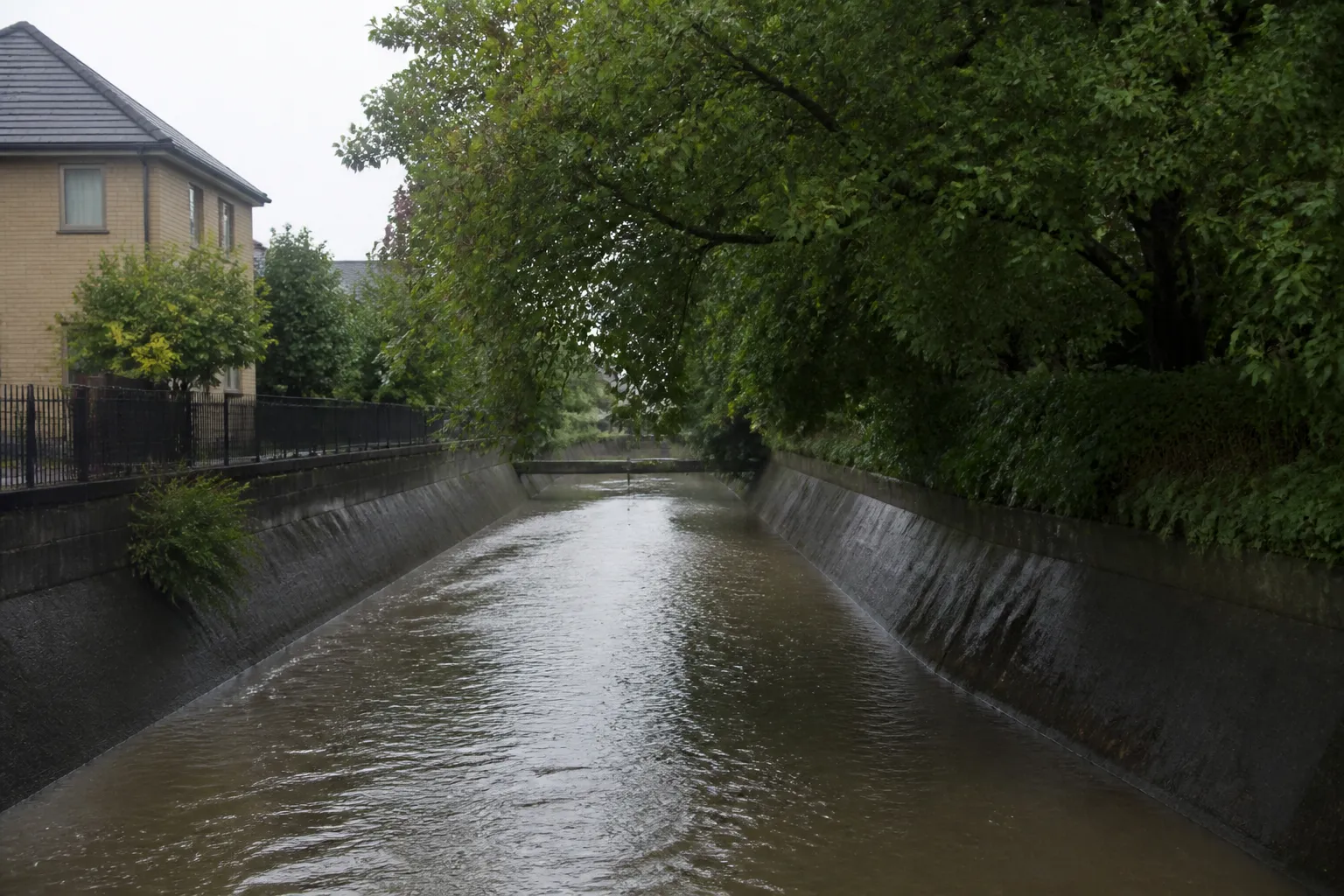 Ruisseau urbain canalisé entre des berges bétonnées après la pluie