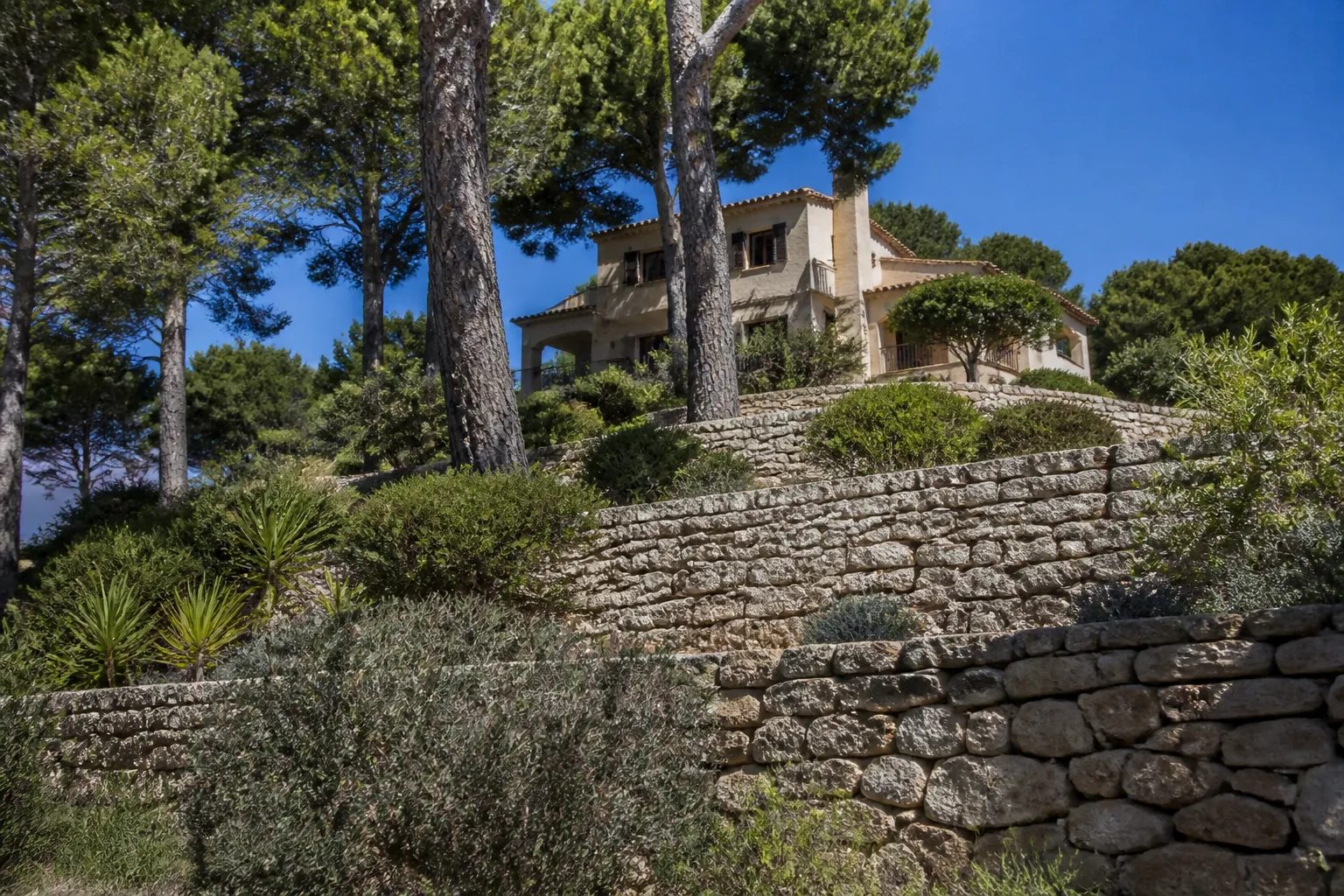 Maison accrochée à une colline avec mur de soutènement en pierre