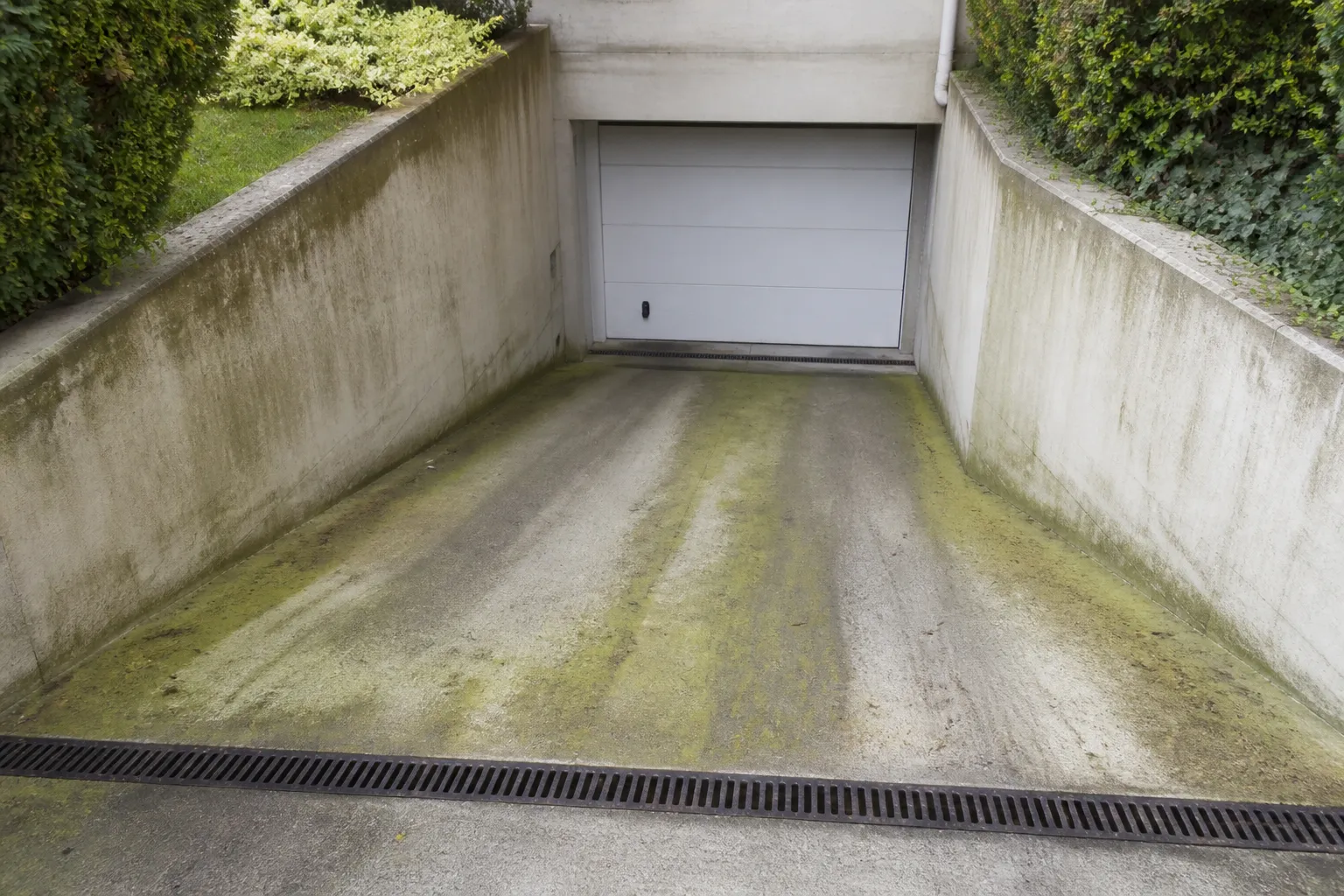 Descente de garage en pente vers une porte de sous-sol avec caniveau