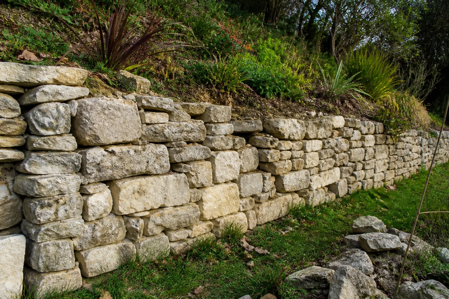 Mur de soutènement en pierres sèches au bord d’un jardin en pente
