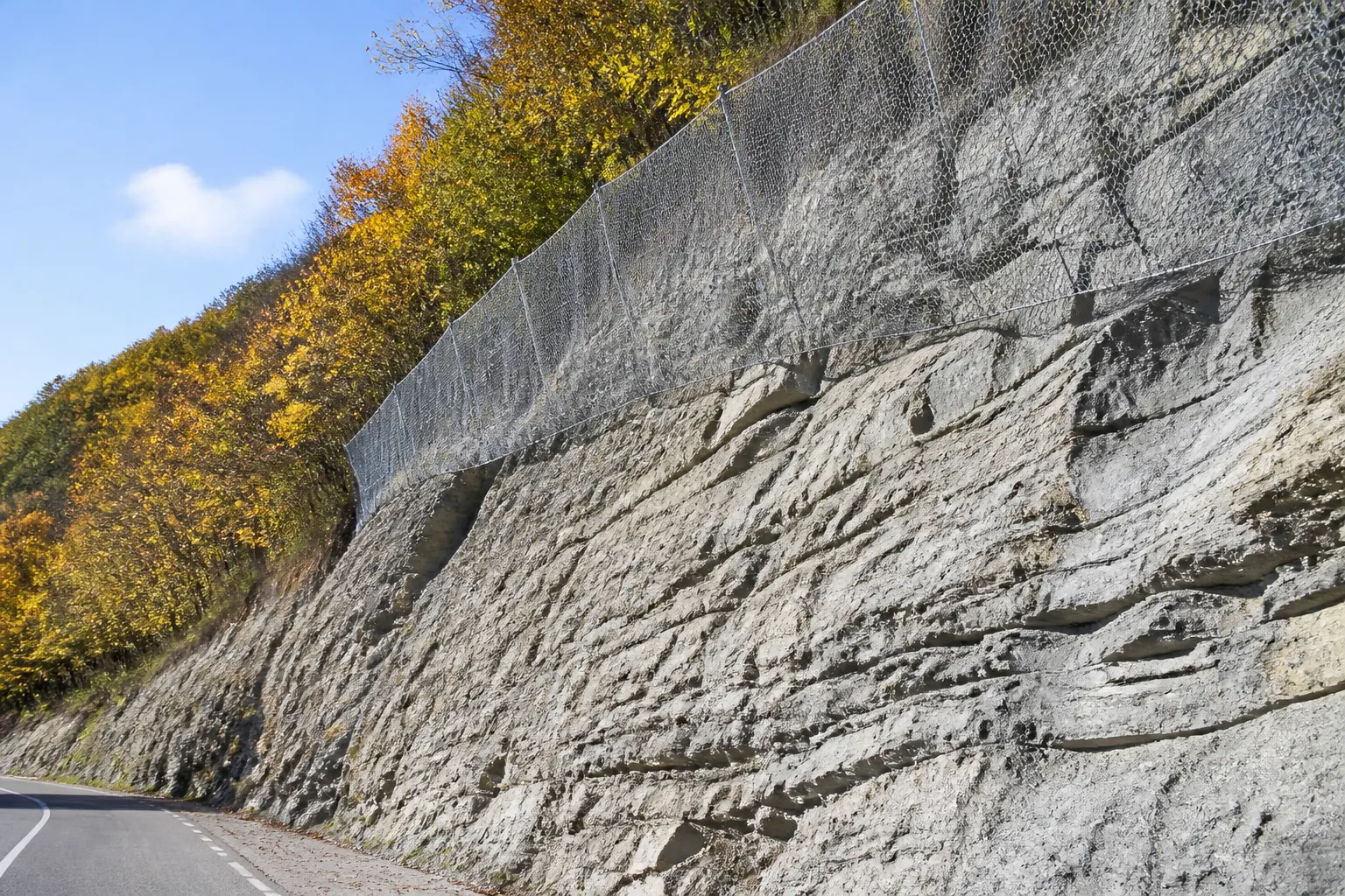 Talus rocheux calcaire avec filet de protection au-dessus d’une route