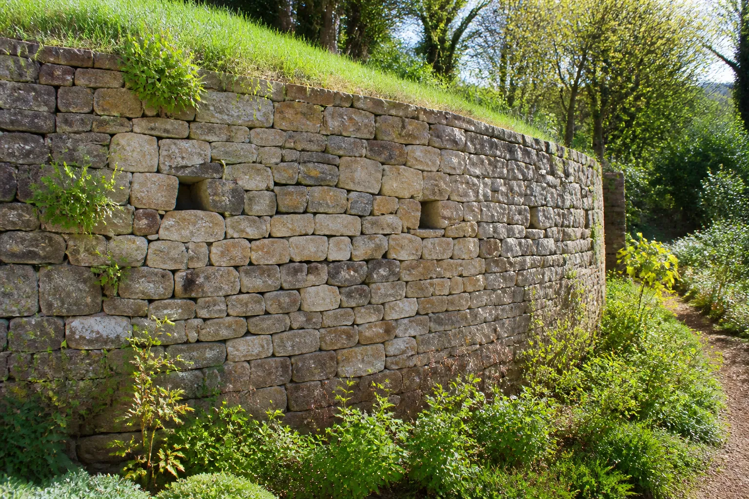 Mur de soutènement en pierre avec barbacanes dans un jardin en pente