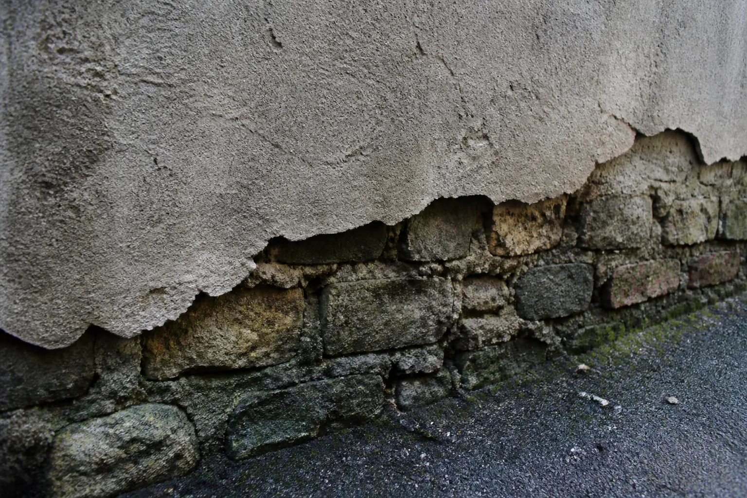 Enduit ciment qui se décolle d'un mur en pierre humide