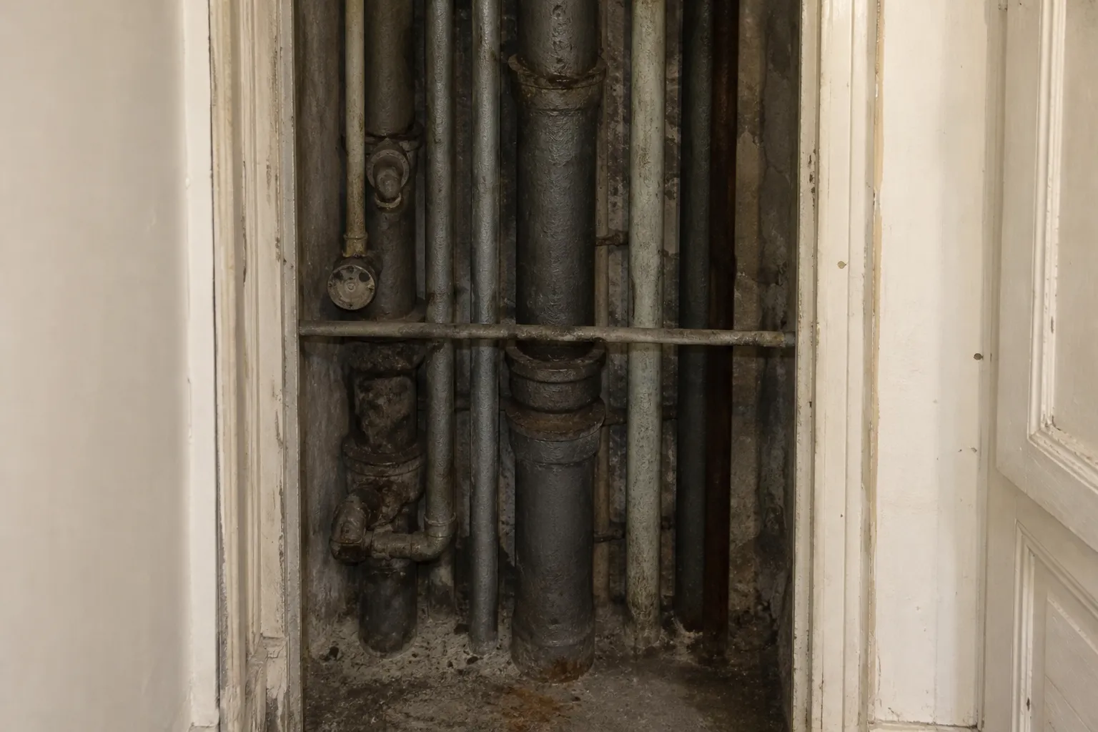Gaine technique avec colonnes d'eau anciennes dans un immeuble