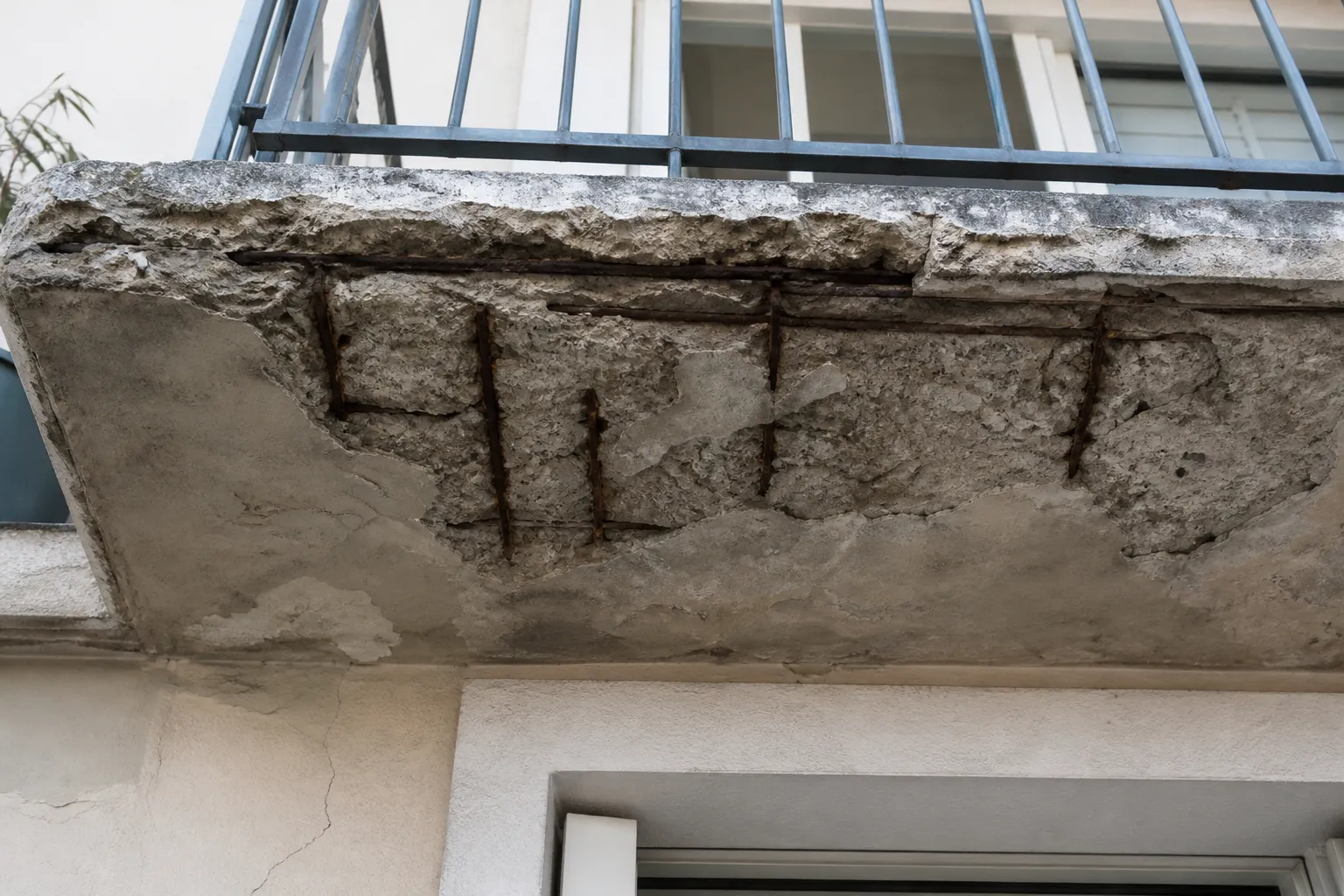 Balcon en béton avec épaufrures et armatures apparentes