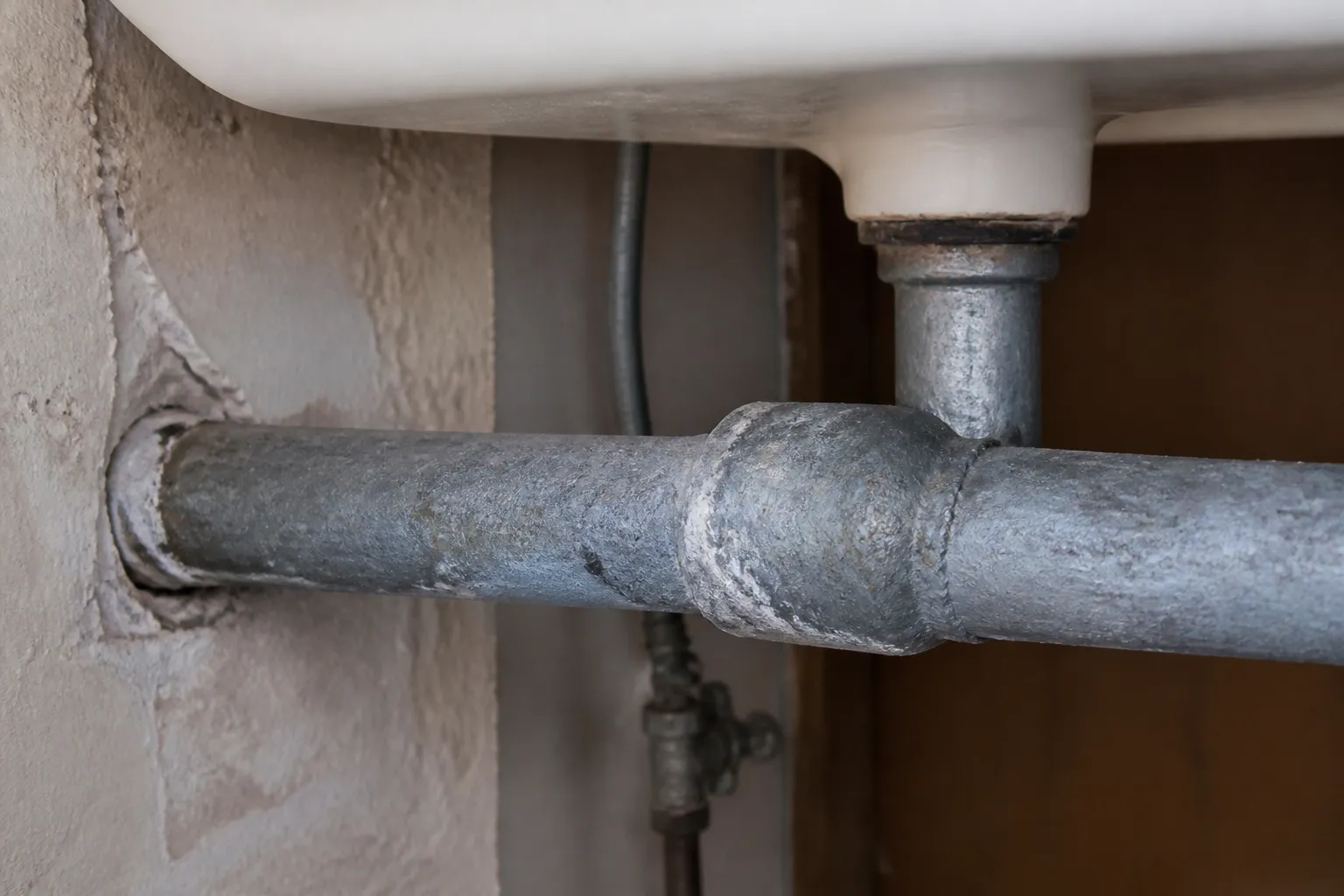 Canalisation d'eau ancienne en plomb sous un évier