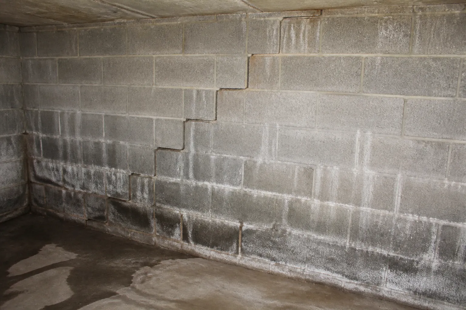 Mur enterré de sous-sol avec traces d'humidité et fissure